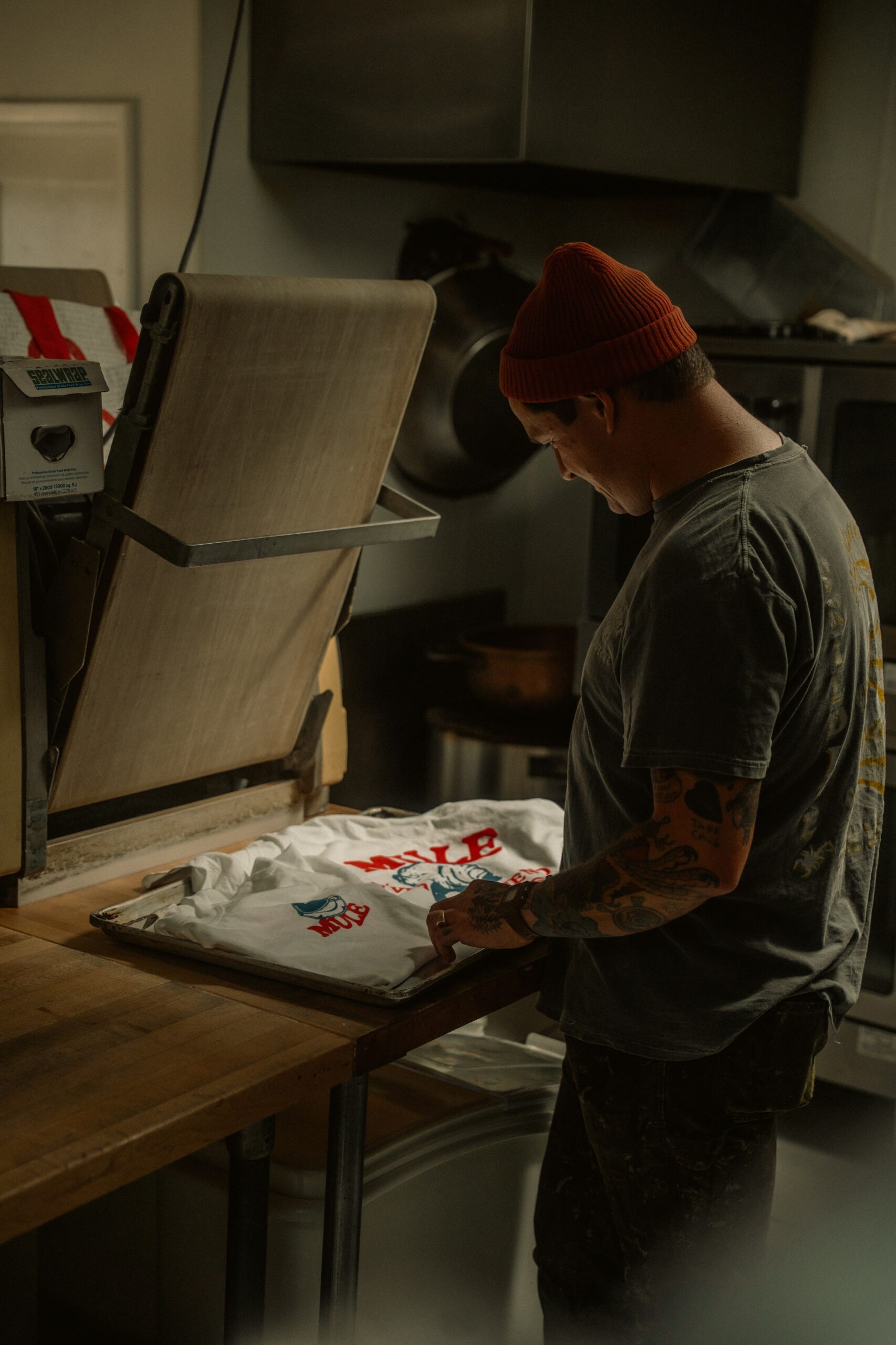 ¿Por qué la Hotronix Fusion IQ es diferente al resto? - Hombre adulto imprimiendo camiseta personalizada con prensa de calor en taller oscuro