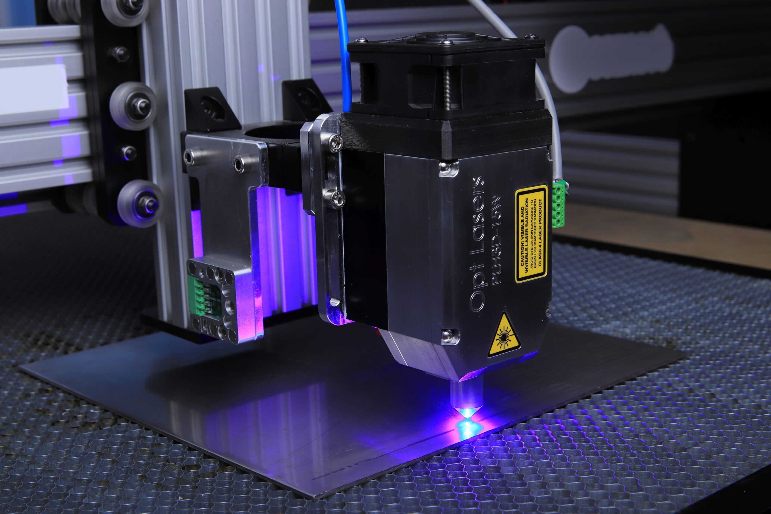 xTool F1 Ultra - Primer plano de máquina láser de fibra grabando superficie metálica con luz azul