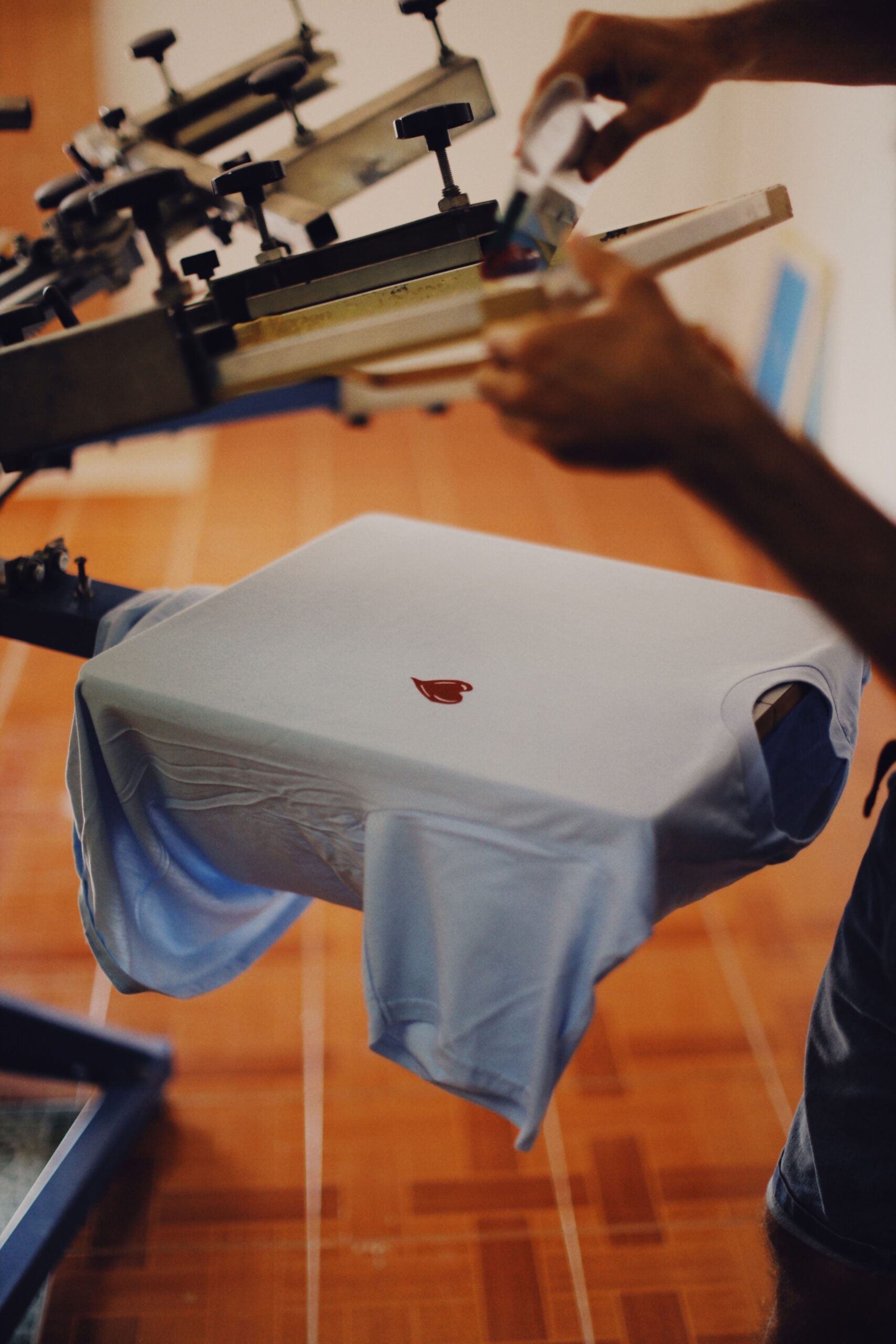 Serigrafia automatica M&R - Primer plano de hombre usando máquina de serigrafía industrial para impresión de camisetas